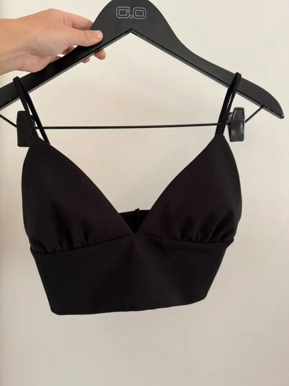 Top negro con breteles finos y escote en V. Ideal para combinar con jeans o faldas para un look moderno y versátil.