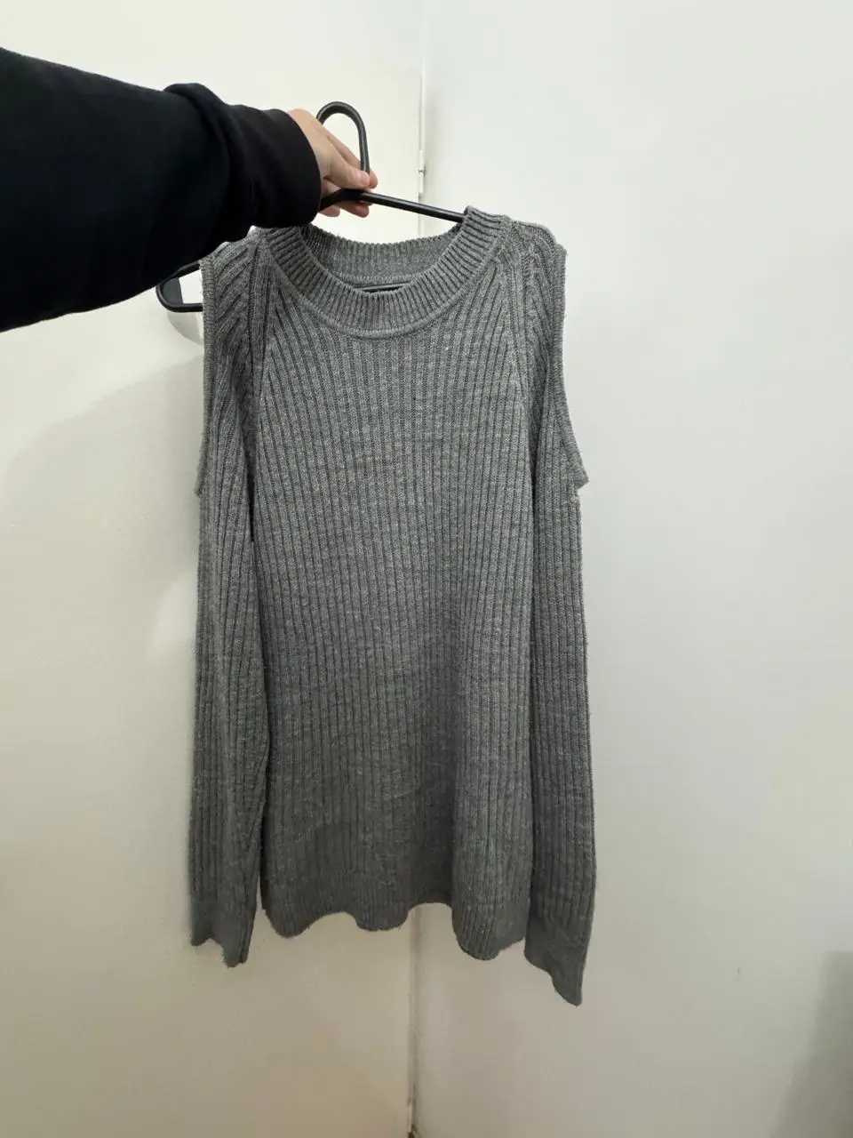 Sweater gris de lana con hombros descubiertos. Ideal para un look moderno y abrigado.