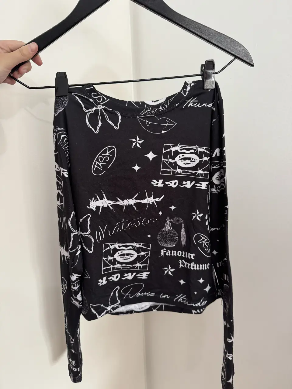 Remera manga larga negra con estampado blanco de diseños variados, ideal para un look urbano y moderno.