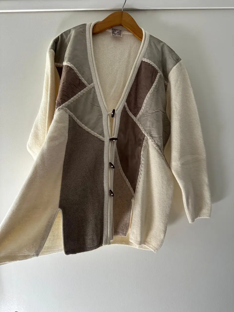 Cardigan de lana con diseño patchwork en tonos neutros. Cierre con botones de madera y detalles artesanales.
