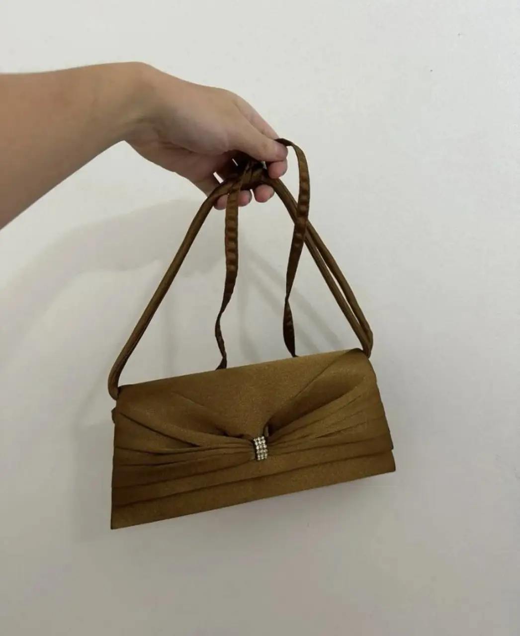 Cartera de mano dorada con detalle de strass. Ideal para eventos formales y fiestas.