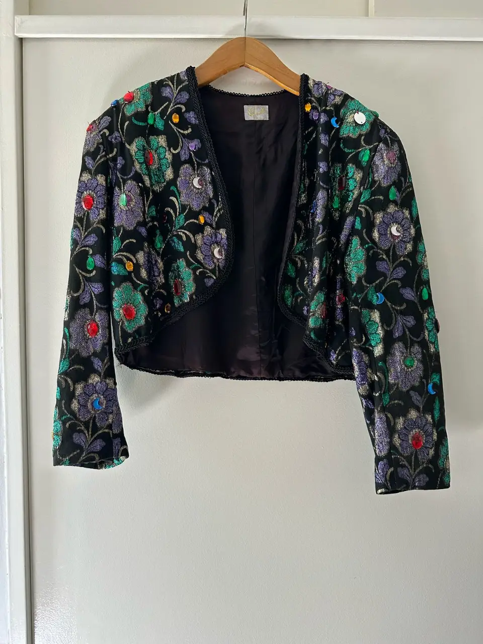 Chaqueta bolero vintage con bordados florales y apliques de piedras. Ideal para darle un toque único a cualquier look de fiesta.