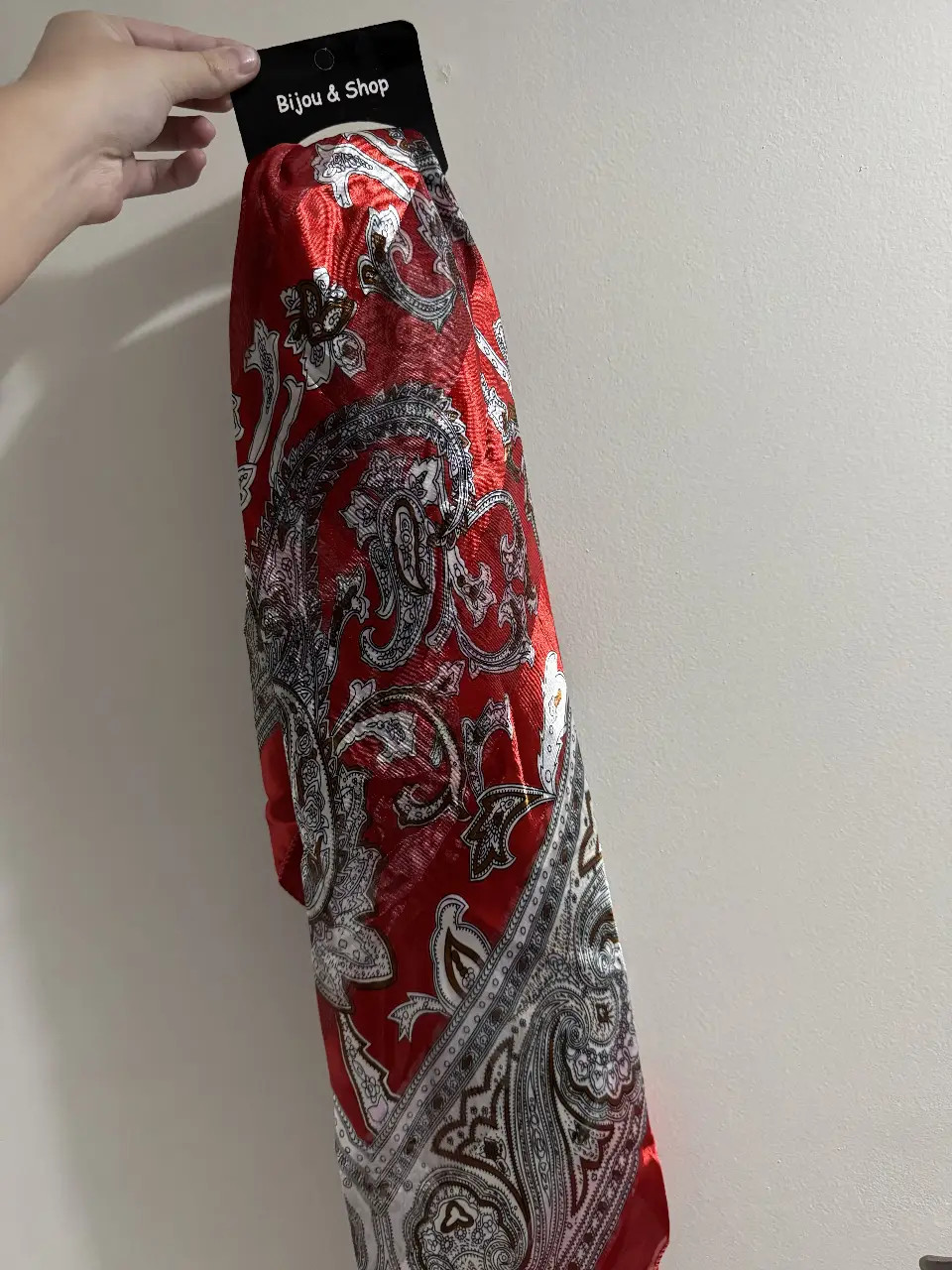 Pañuelo de seda rojo con estampado de diseño paisley en blanco y negro, ideal para complementar cualquier look femenino.