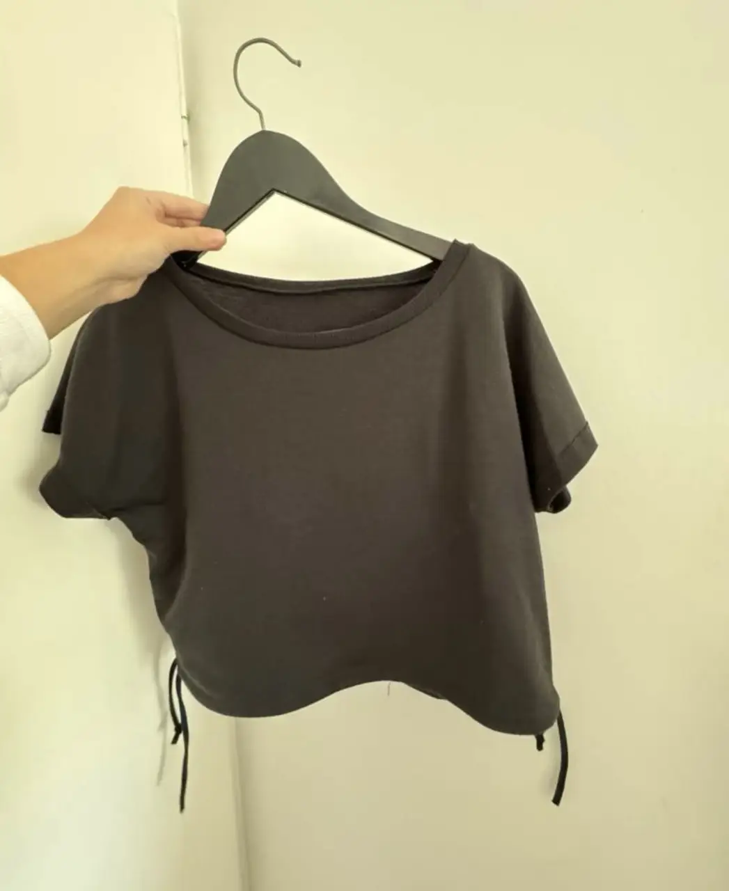 Top negro corto con detalles de ajuste en los laterales. Ideal para un look casual y moderno.