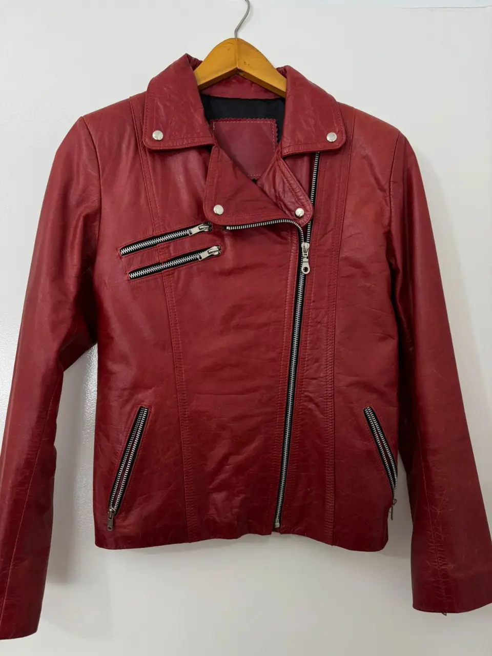 Campera biker de cuero roja, con cierre asimétrico y detalles metálicos. Talle M.