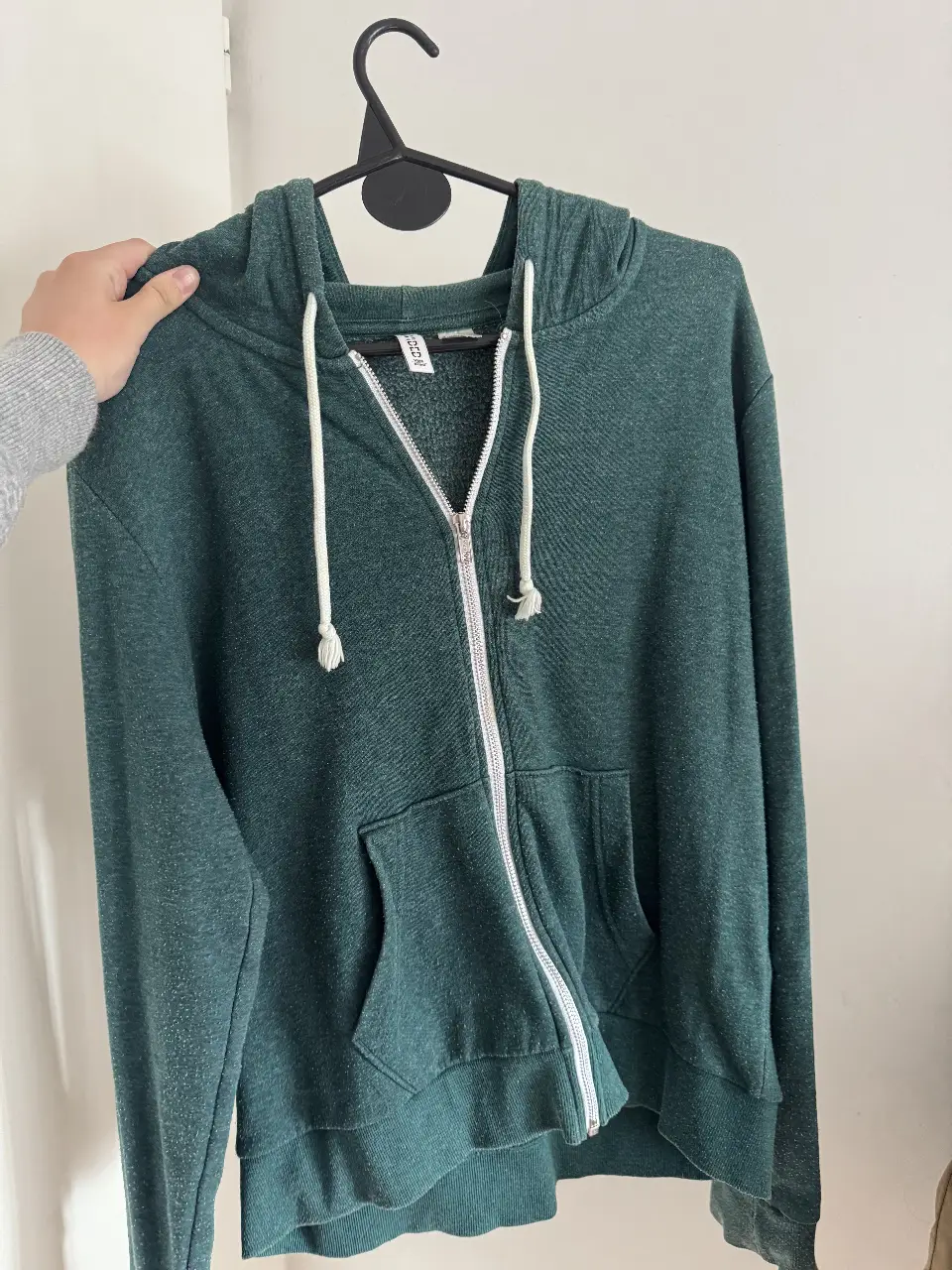 Buzo con cierre y capucha, de color verde oscuro. Ideal para un look casual y cómodo.
