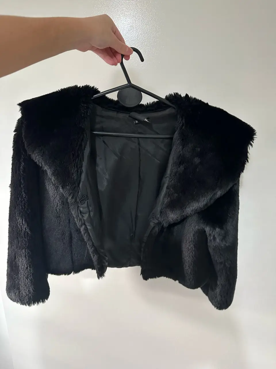 Campera de piel sintética negra, estilo biker, con cuello solapa y detalles de botones. Ideal para un look moderno y abrigado.