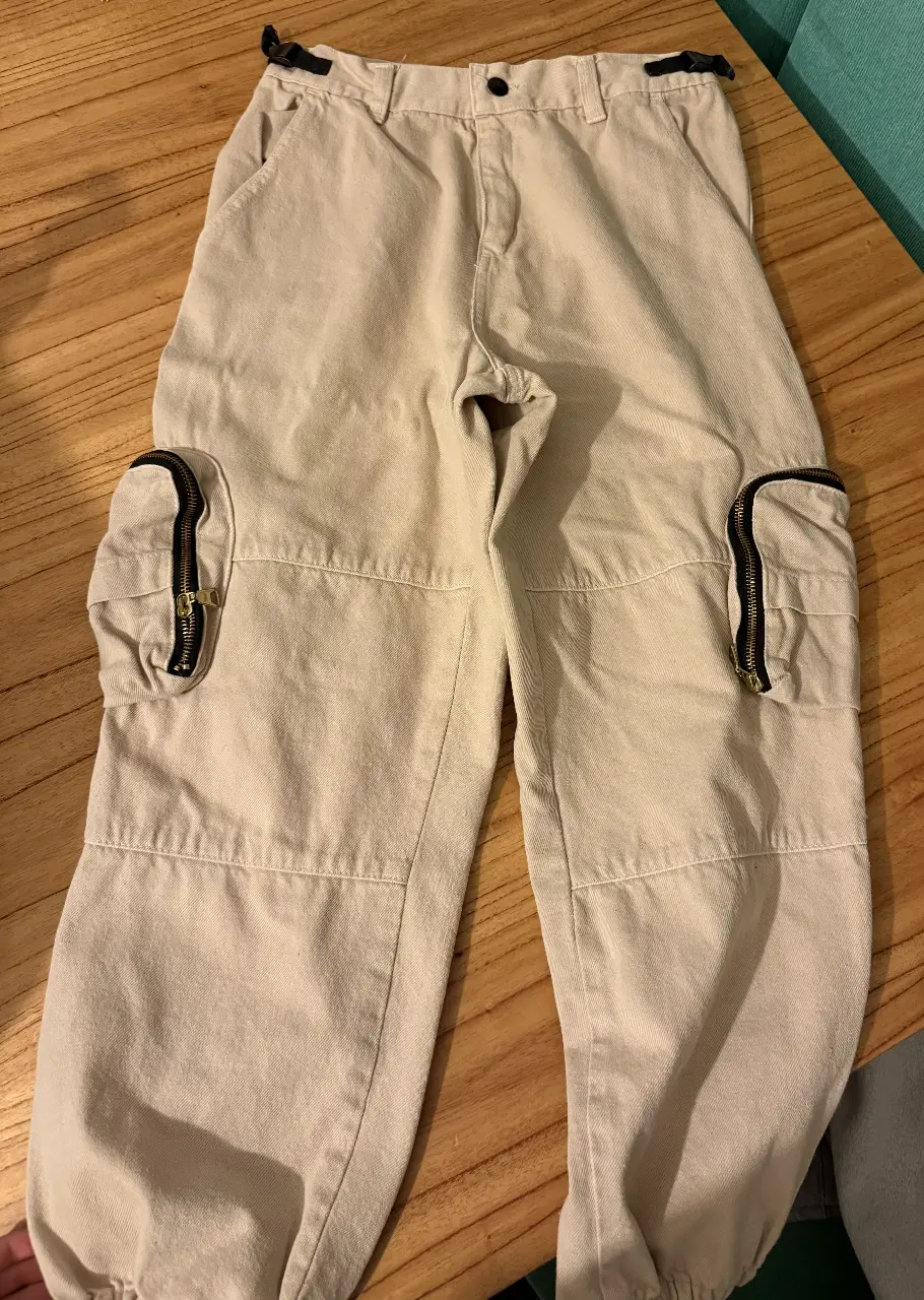 Pantalón cargo tiro bajo de gabardina color crudo con bolsillos laterales con cierre. Talle 1. 