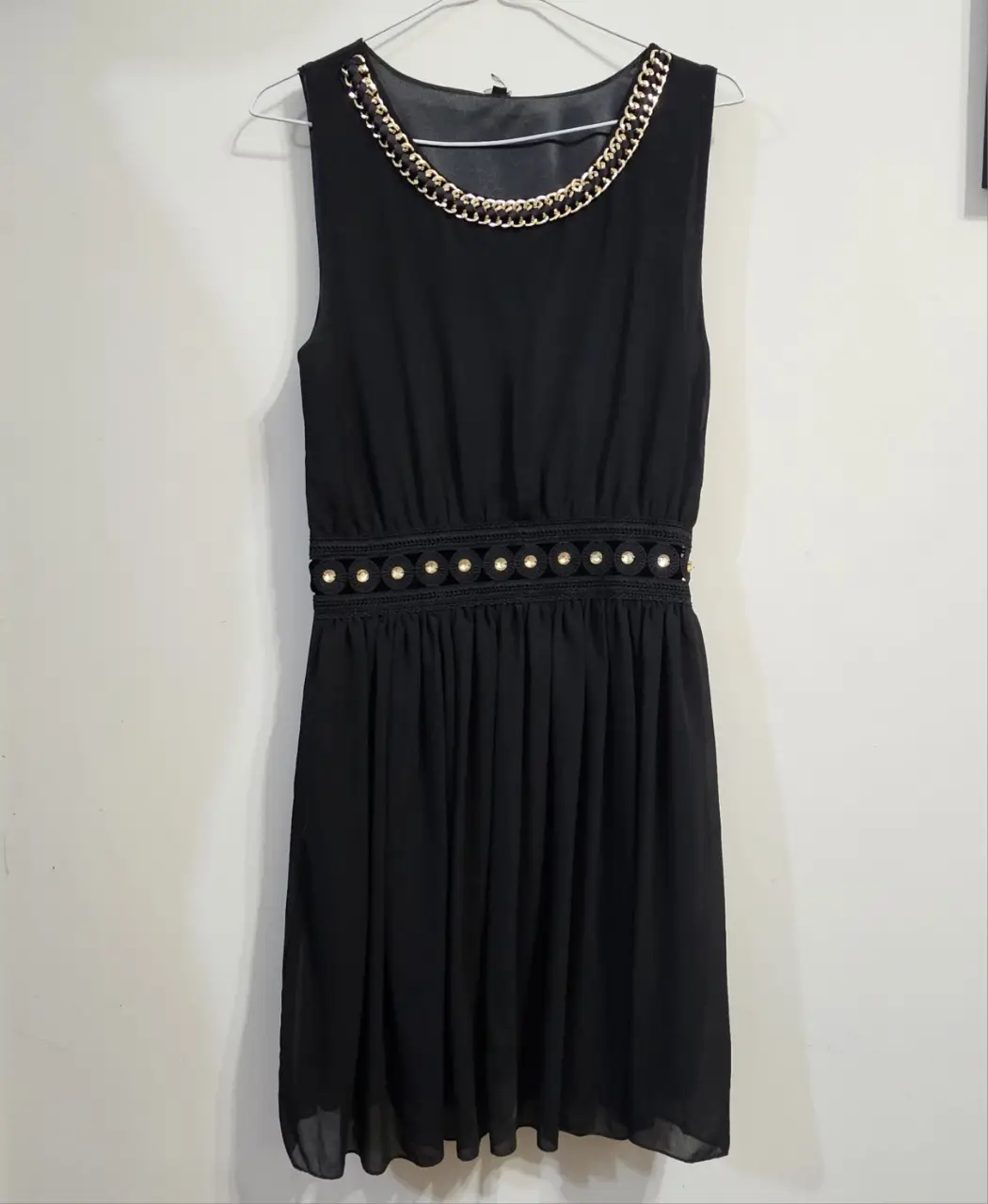 Vestido negro corto con detalle de cadena dorada en cuello y cinturón con apliques dorados ( transparente). Ideal para fiestas y salidas. Gasa y forro del mismo color. No te hacen falta accesorios, ya esta listo para lucirte. T. Unico
