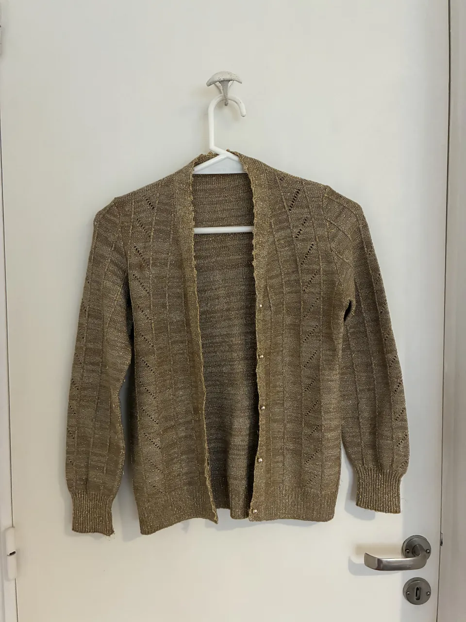 Cardigan tejido color dorado con detalles metalizados y botones dorados. Ideal para un look elegante y sofisticado.