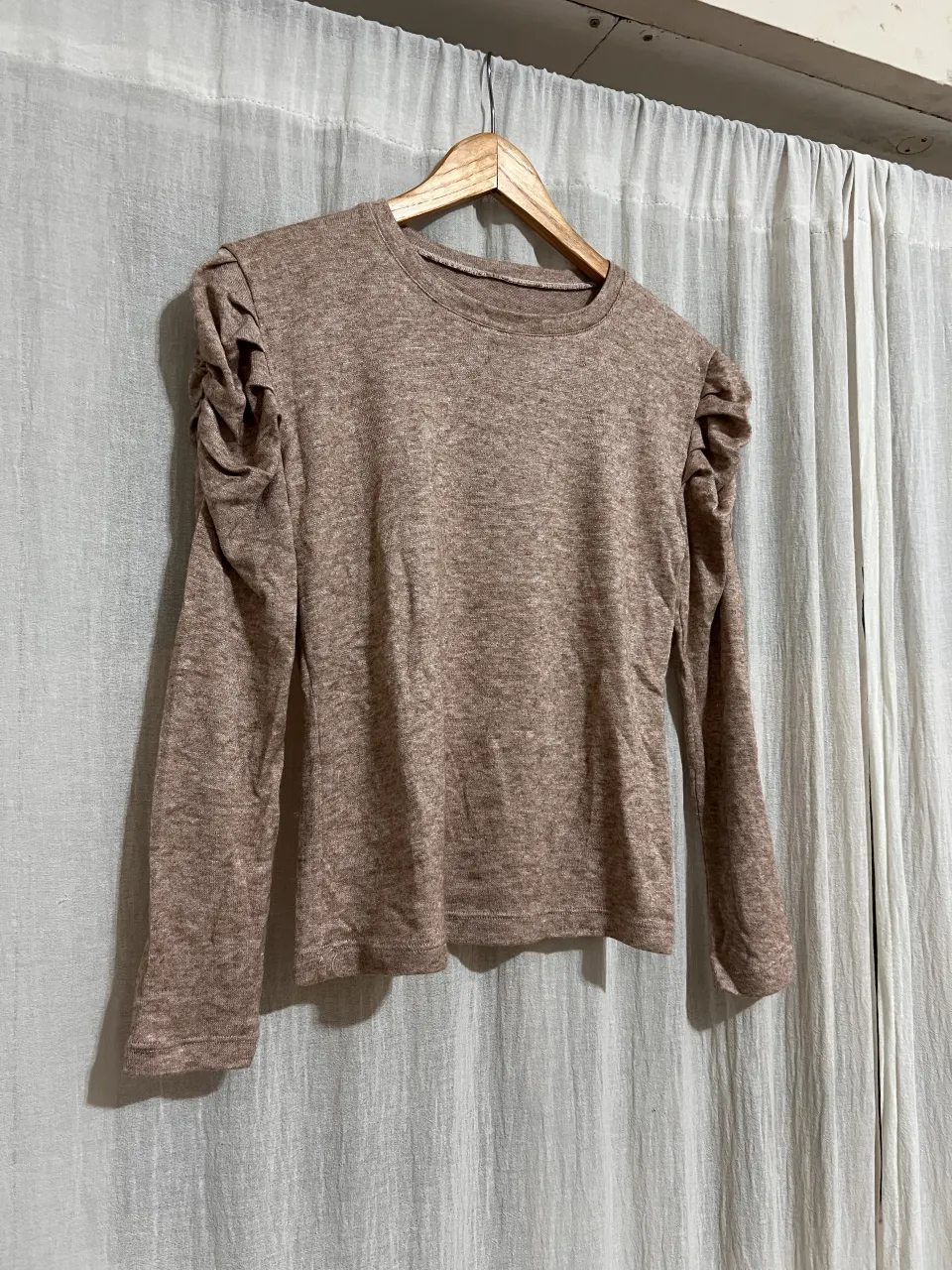 Remera manga larga de lanilla color tiza con detalles de fruncido en los hombros. Ideal para un look casual y cómodo.