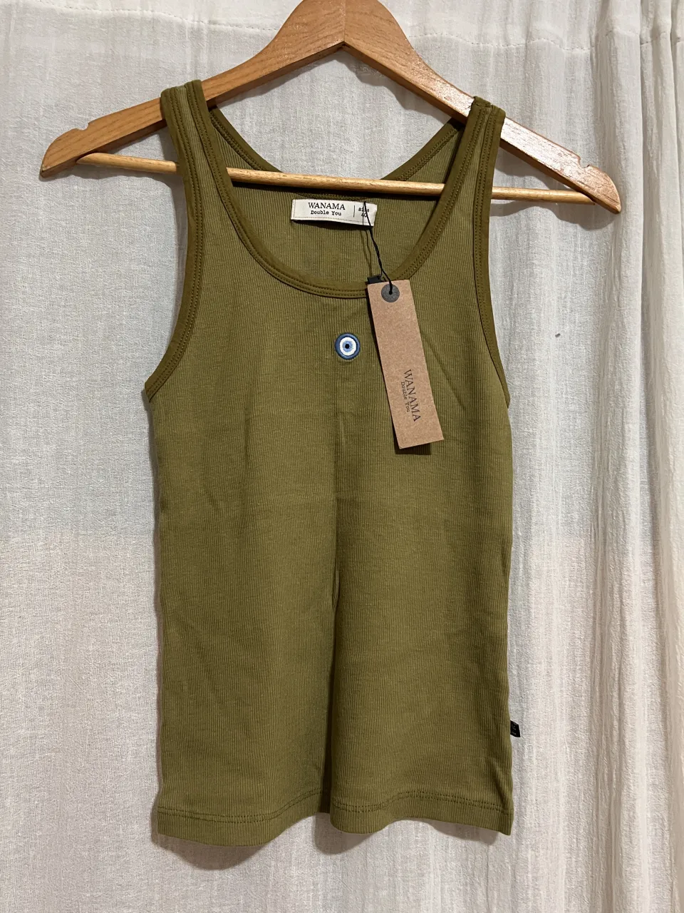 Musculosa de algodón acanalada en color verde militar. Posee un detalle bordado de un ojo turco en la parte delantera. Perfecta para un look casual y moderno.