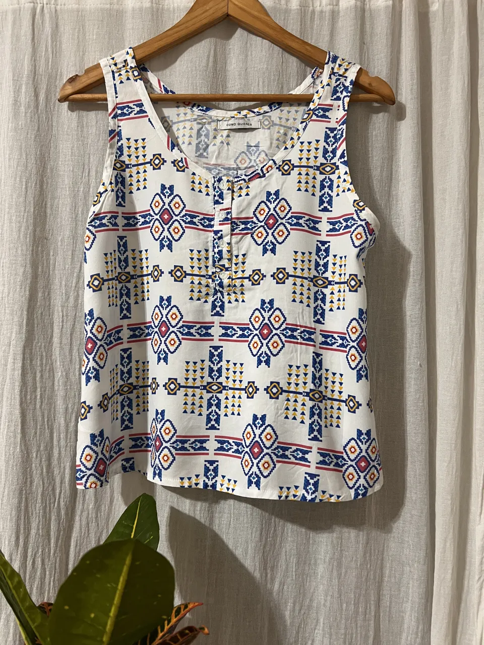 Musculosa blanca con estampa geométrica estilo étnico en tonos azul, rojo y amarillo. Posee botones en la parte superior del escote.