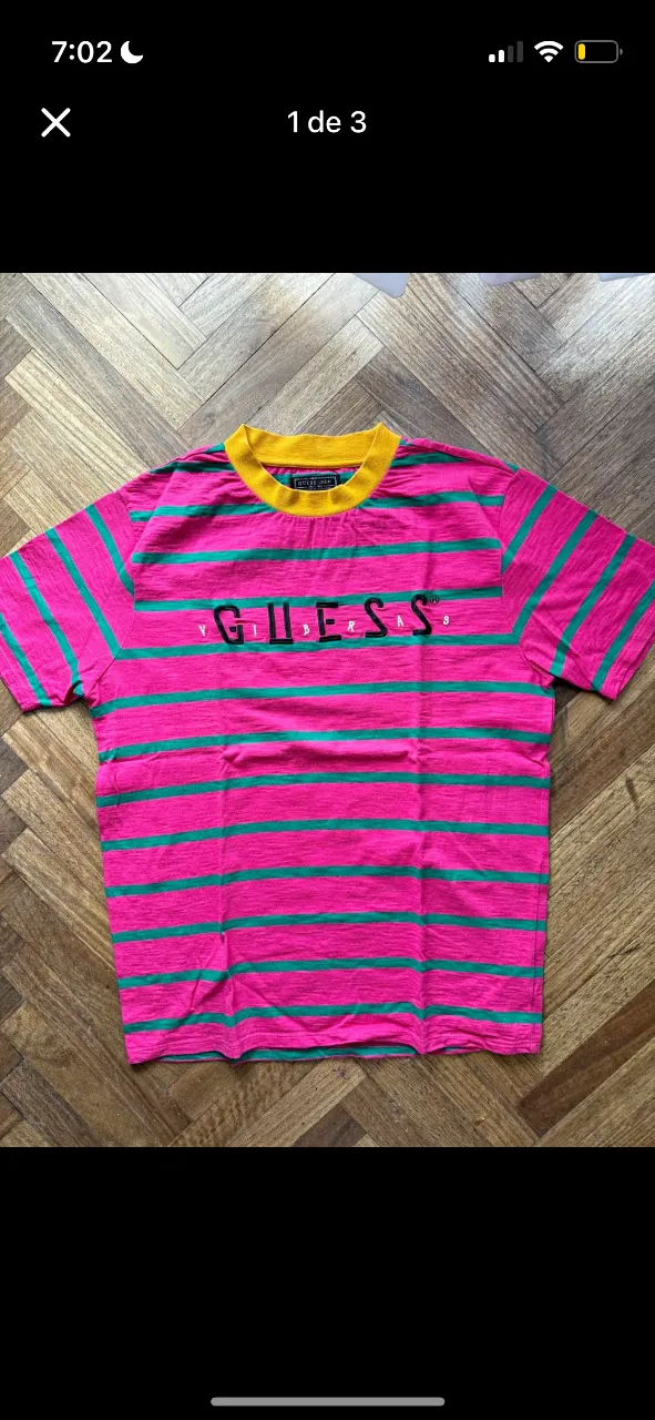 Remera a rayas fucsia y verde con cuello amarillo. Estampado 'GUESS VIBES' en el frente. Ideal para un look urbano y canchero.