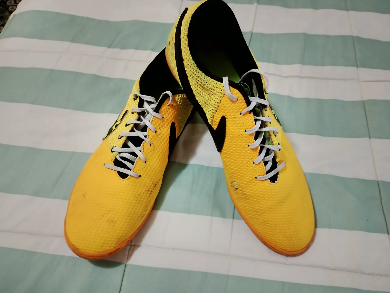 Zapatillas de fútbol Nike amarillas con detalles en negro y suela naranja. Ideales para jugar en canchas de interior o césped sintético. ¡Listas para la acción!