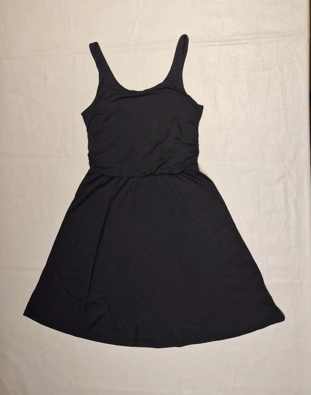Vestido negro corto tipo musculosa, con corte en la cintura y falda con vuelo. Ideal para un look casual y fresco.