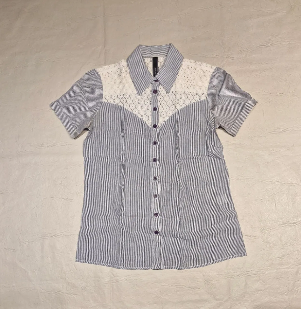 Camisa de mujer a rayas celeste y blanco con detalles de encaje blanco en el frente y espalda. Mangas cortas. Ideal para un look casual y fresco.
