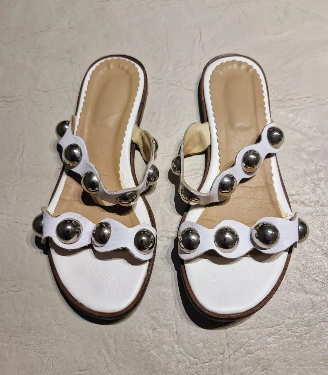 Sandalias blancas chatas con detalles de tachas plateadas. Muy poco uso. Ideales para un look casual y moderno.