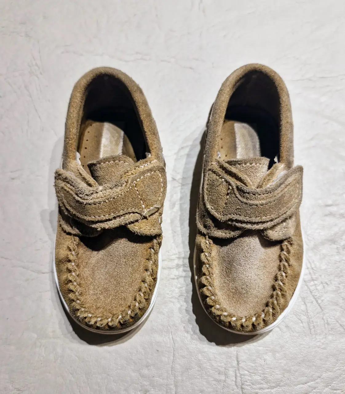 Zapatos mocasines para niño, color baige con suela blanco y cierre de velcro. Ideales para un look casual y cómodo.