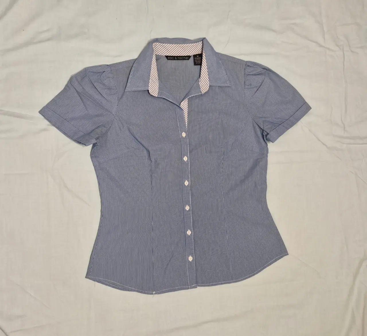 Blusa de mujer a rayas celestes y blancas, con mangas cortas abullonadas y cuello con detalles en contraste. Medidas tomadas en plano: 50 cm de axila a axila, 43 cm de cintura (tomada a la altura del 3er botón, comenzando desde abajo). 60 cm largo de espalda desde la base del cuello (4ta foto)