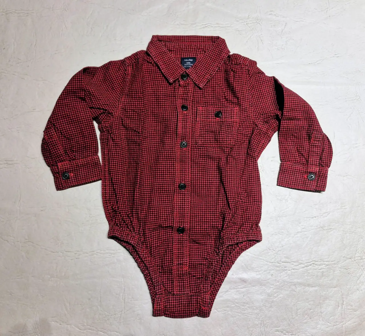 Body camisa a cuadros rojo y negro manga larga para bebé. Ideal para un look casual y cómodo.
