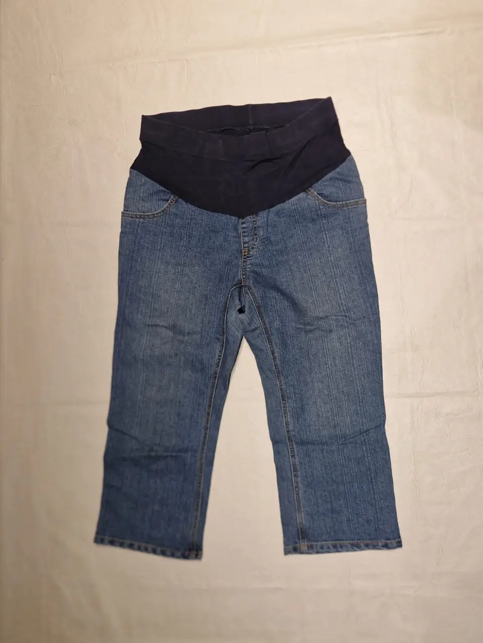 Pantalón de jean premamá, corte capri. Posee un panel de tela elástica en la cintura para mayor comodidad durante el embarazo. Ideal para un look casual y cómodo.