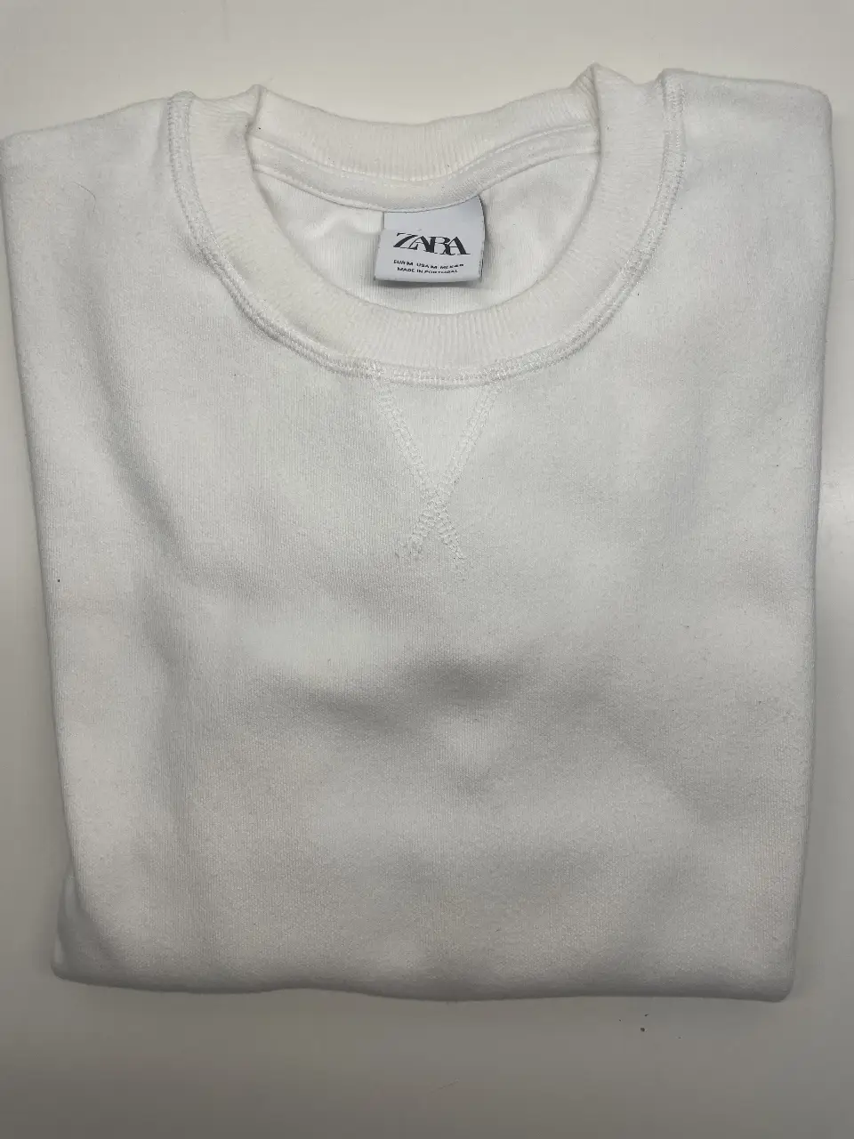 Buzo de cuello redondo blanco de la marca Zara, ideal para un look casual y cómodo. Perfecto para el día a día.