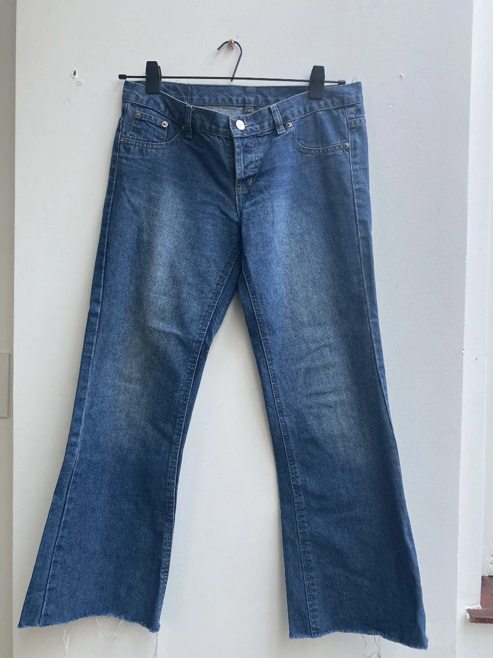 Jeans rectos de denim azul, con detalles de costura en bolsillos traseros y cierre con botón metálico. Un clásico para cualquier ocasión. tiro bajo