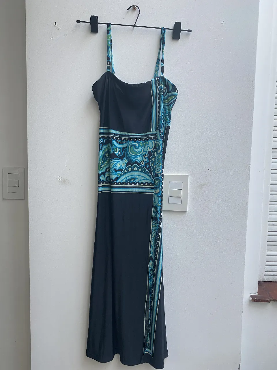 Vestido midi negro con estampado en tonos azules y detalles en blanco. Diseño con tirantes finos y un corte elegante, ideal para lucir en ocasiones especiales.