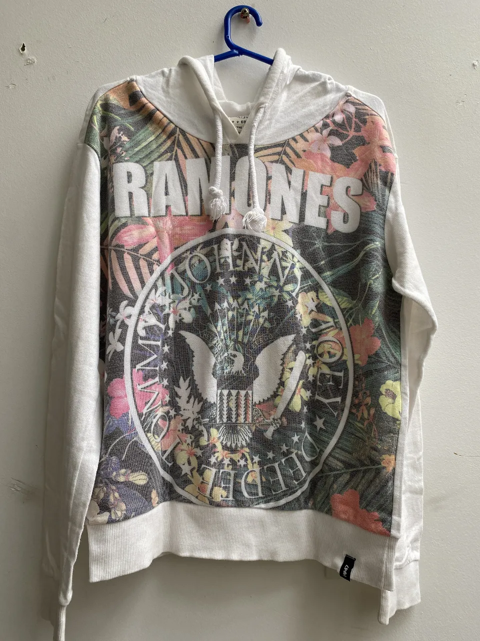 Buzo canguro blanco con estampado de Ramones en el frente y detalles florales. Ideal para un look casual y rockero. talle 1 