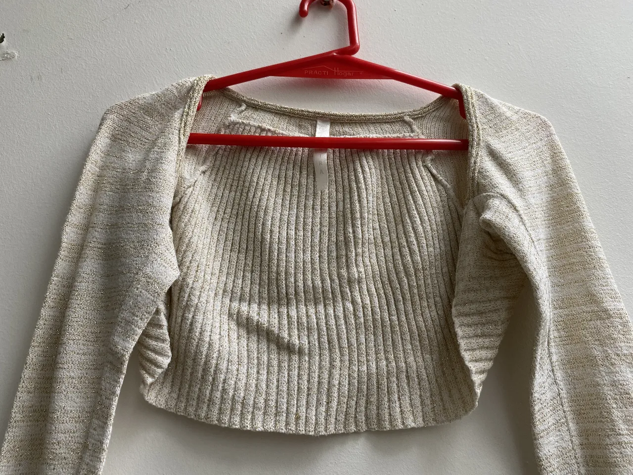Sweater crop de tejido acanalado en color crudo con detalles dorados. Ideal para un look elegante y moderno. Marca Ossira Talle S