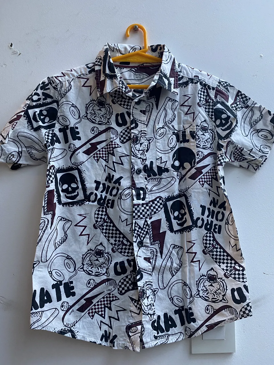 Camisa de manga corta para niño con estampado de skate, calaveras y otros diseños. Ideal para un look casual y moderno.