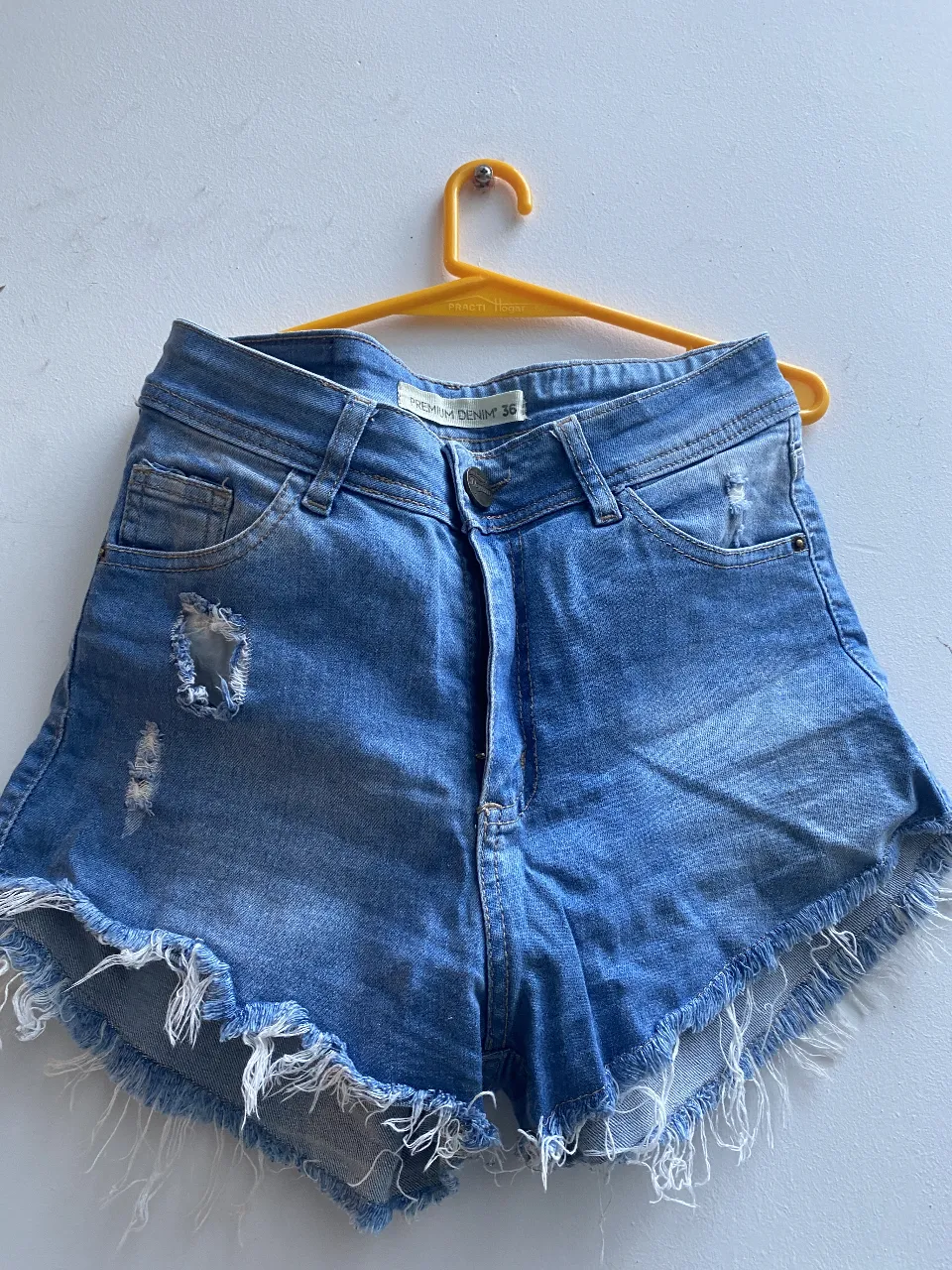 Short de jean de mujer, tiro medio, con roturas y flecos en el borde. Ideal para un look casual y moderno. Talle 36