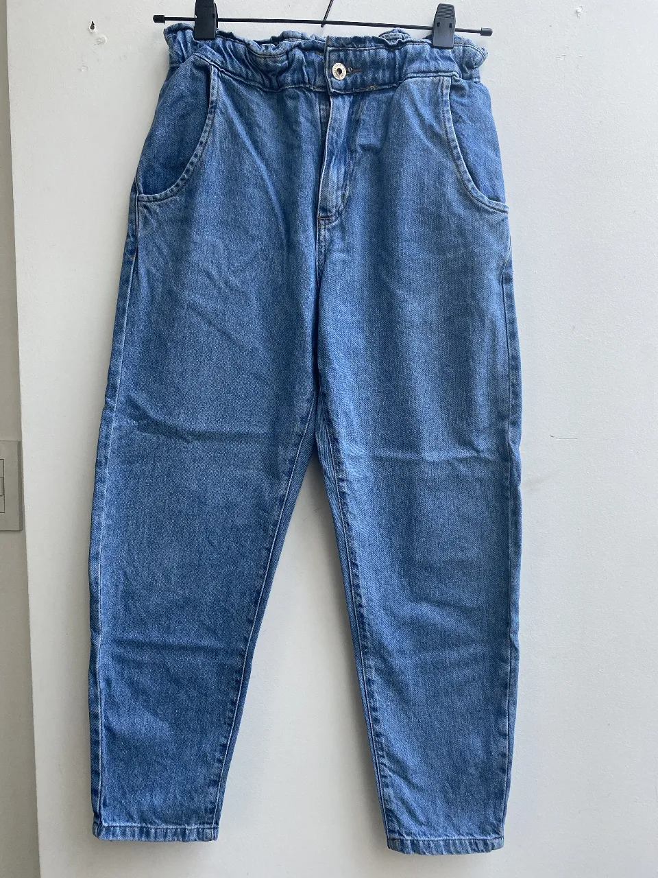Pantalón de jean azul, tiro alto, con cintura elastizada y bolsillos delanteros. Talle 26. corte baggy