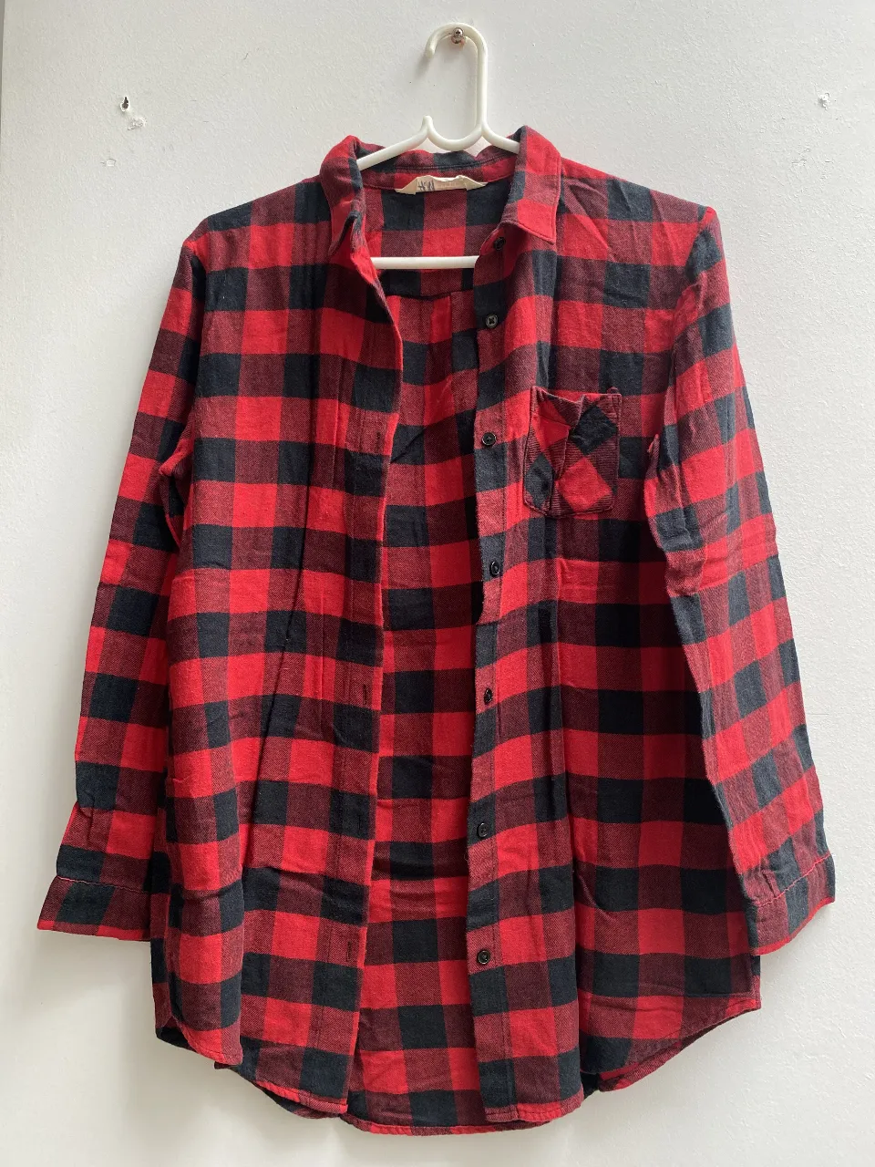 Camisa de leñador a cuadros rojos y negros, de manga larga, con bolsillo en el pecho. Ideal para un look casual y abrigado.
