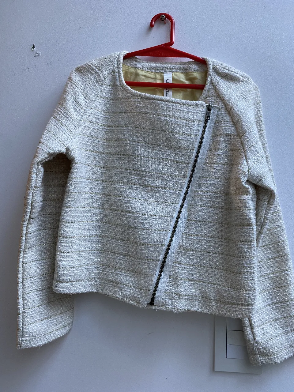 Campera bomber de niña tela de punto  en color crudo con detalles dorados. Diseño asimétrico con cierre y cuello redondo. Ideal para un look moderno y sofisticado. Talle 10/12