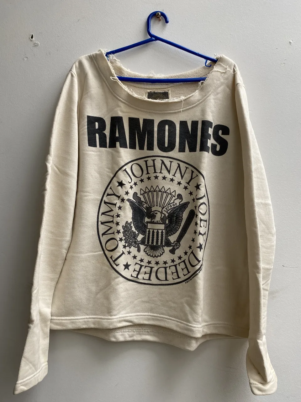 Buzo de cuello redondo color crudo con estampado de la banda Ramones. Ideal para un look rocker y casual. talle M, tiene una pequeña mancha en la parte de adelante sobre la estampa 