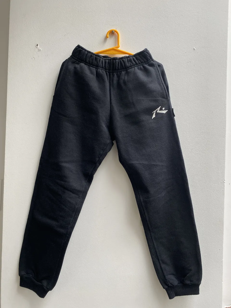 Pantalón de jogging negro de la marca Rusty, ideal para un look casual y cómodo. Confeccionado en tela de algodón suave, este pantalón ofrece un ajuste relajado y un estilo deportivo. Perfecto para usar en cualquier momento del día. Talle 12