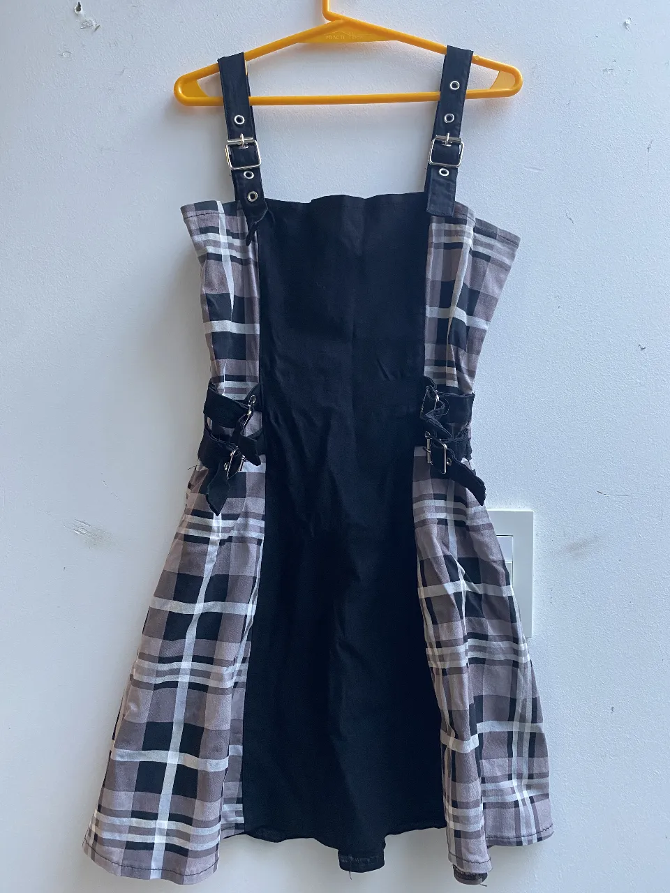 Vestido mini con diseño a cuadros en tonos grises y blancos, con un panel central negro. Detalles de hebillas en los tirantes y laterales. Ideal para un look moderno y audaz. Bond Street