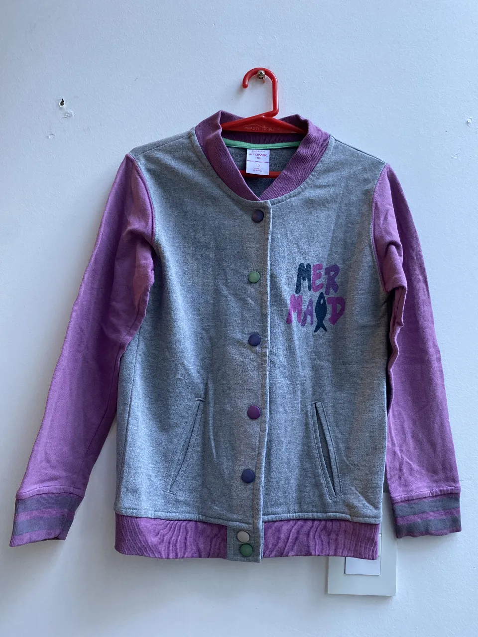Buzo Atomik para niña, con mangas y detalles en violeta, broches a presión. Estampado "Mermaid" en el frente. Talle 10.