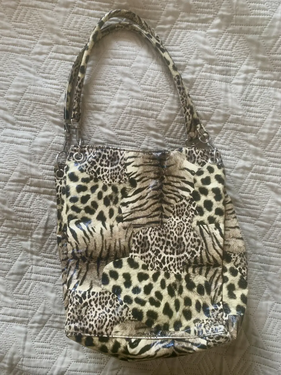 Cartera de hombro con estampado animal print. Diseño con manijas cortas y detalles metálicos. Ideal para un look audaz y moderno.