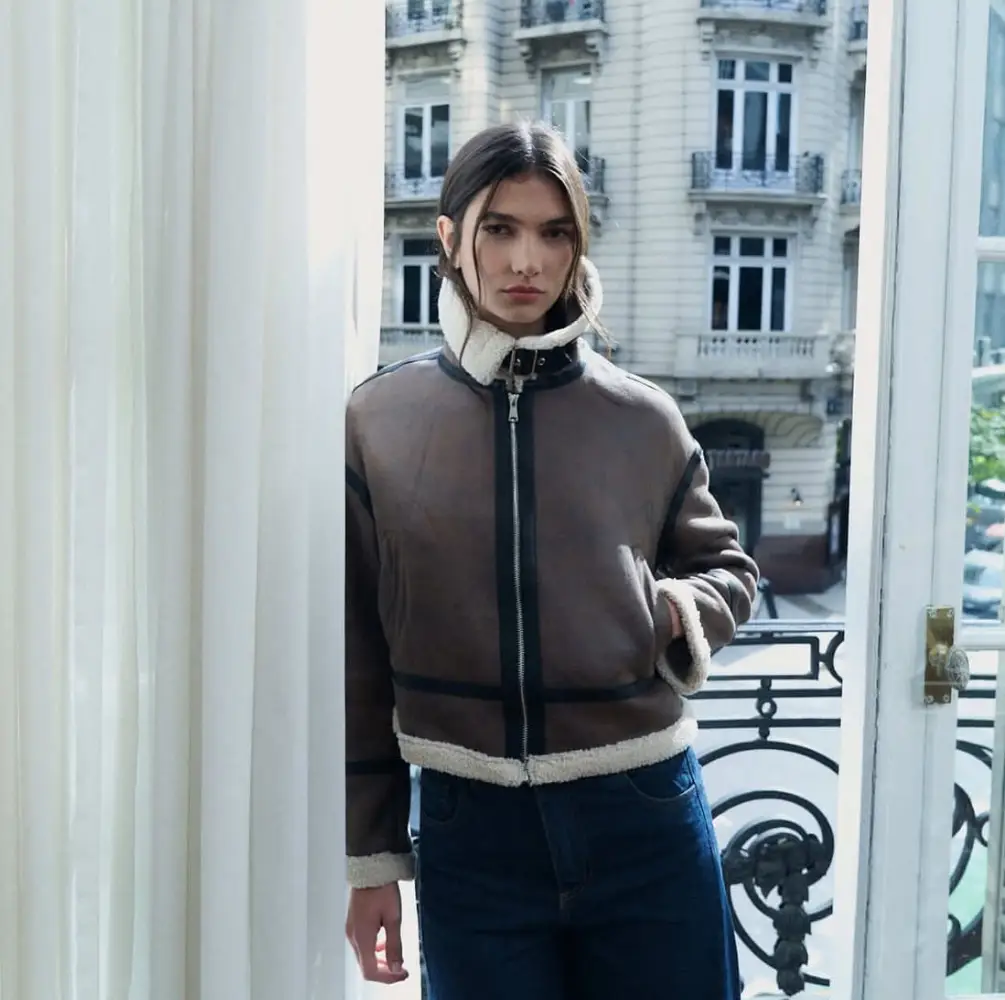 Campera de cuero sintético estilo aviador para mujer. Con forro de piel sintética en el cuello, puños y borde inferior. Cierre con cremallera frontal y detalles de hebillas. Ideal para un look moderno y abrigado.