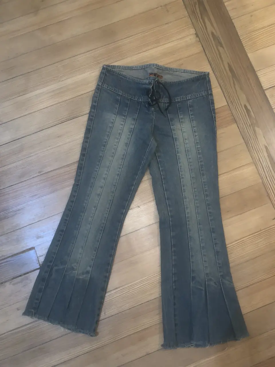Jeans de mujer tiro bajo, con diseño de campana y detalles plisados en las piernas. Posee un cierre con cordón y un estilo Y2K. 82 cm de cintura 