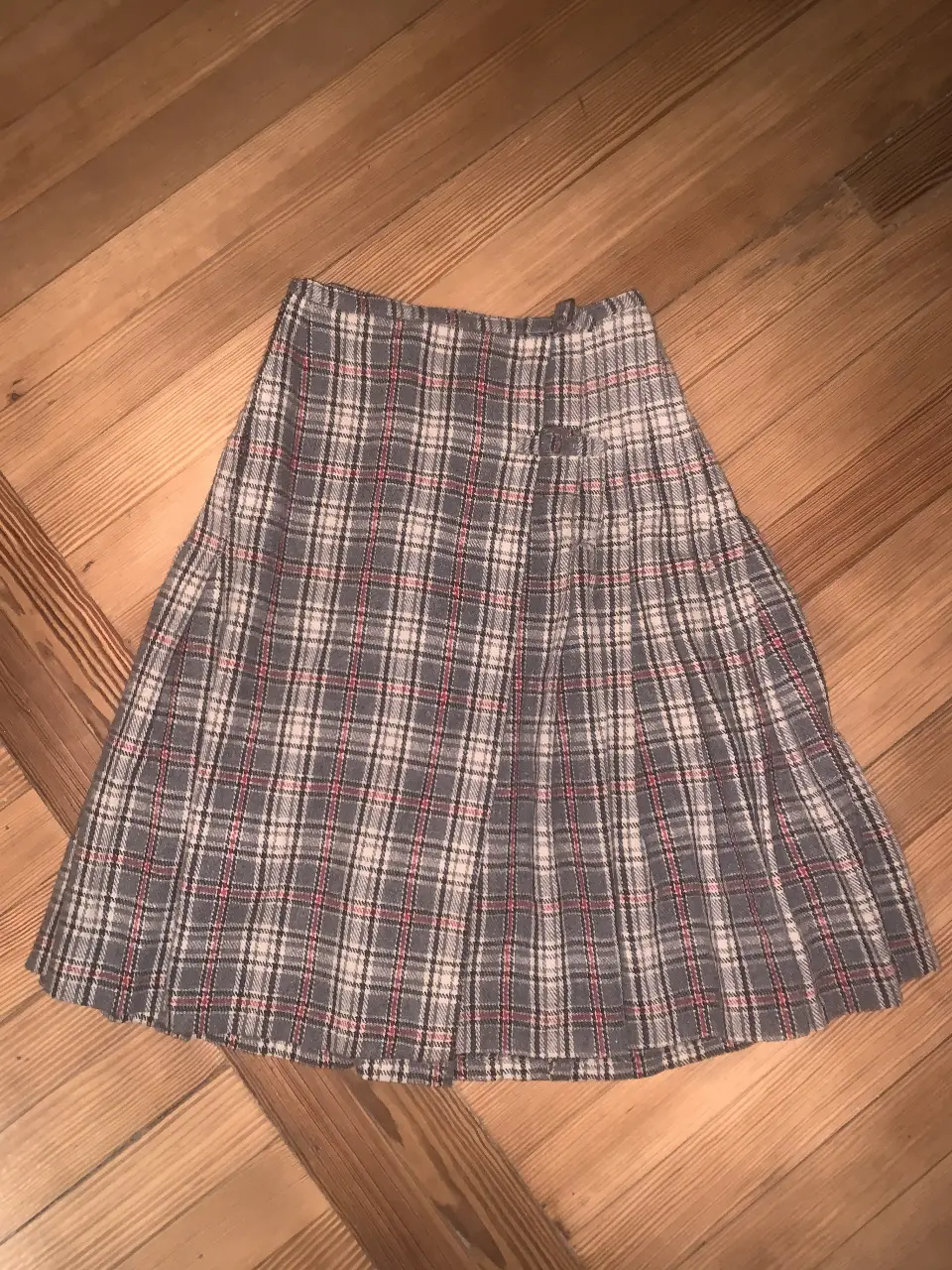 Pollera escocesa gris con detalles en rojo y blanco. Buen estado, se regula los botones, así que va del talle 34 al 38