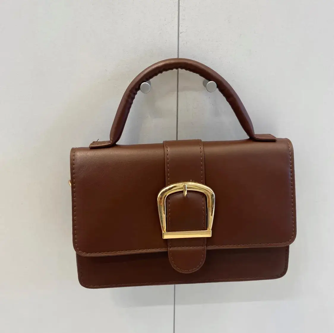 Cartera de mano rectangular de cuero sintético marrón con hebilla dorada. Ideal para un look elegante y sofisticado.