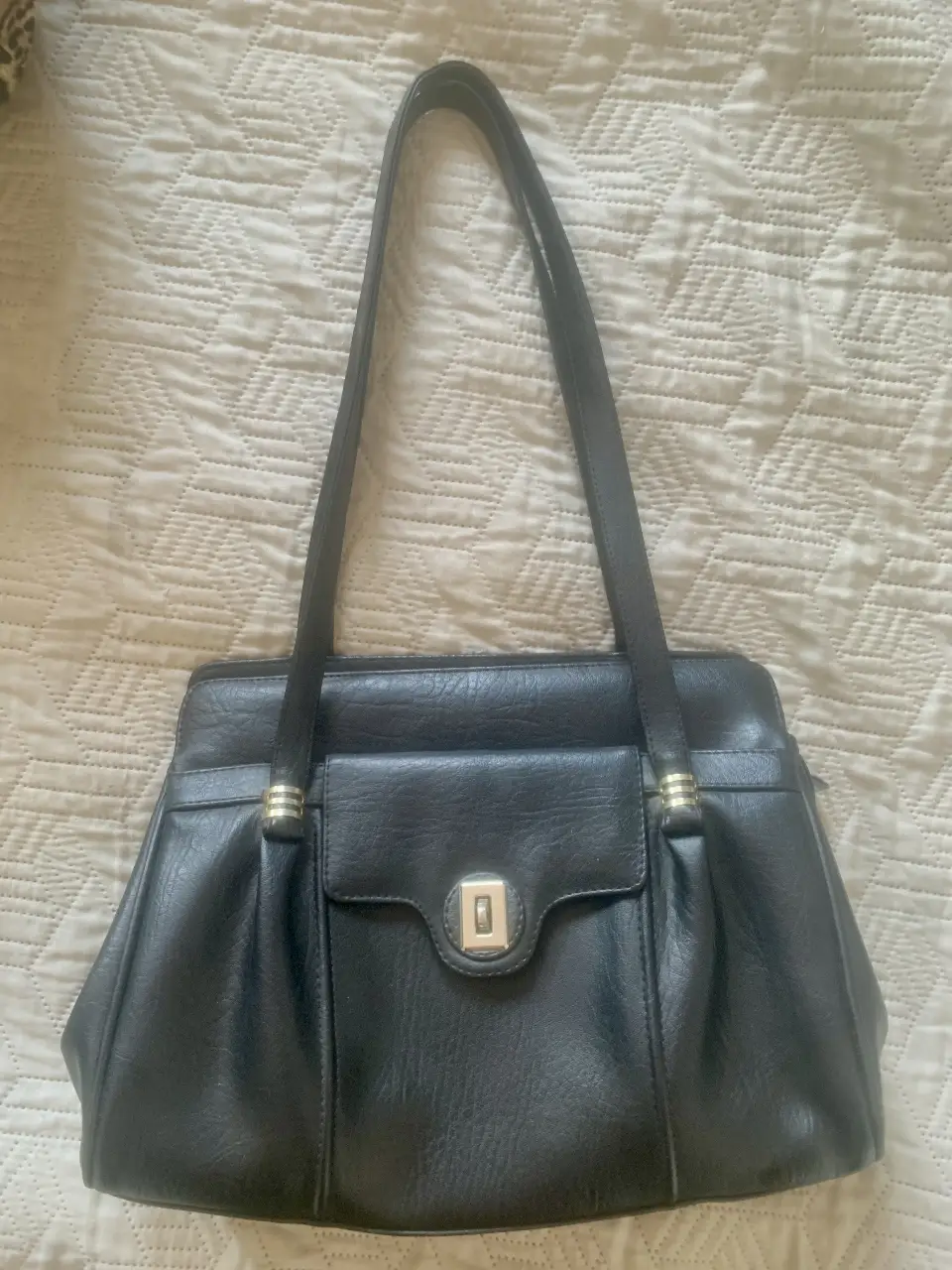 Cartera de hombro negra, con solapa y cierre de botón. Diseño clásico y elegante, ideal para el día a día o para ocasiones especiales. Cuenta con múltiples compartimentos internos para organizar tus pertenencias. Confeccionada en material resistente y duradero.