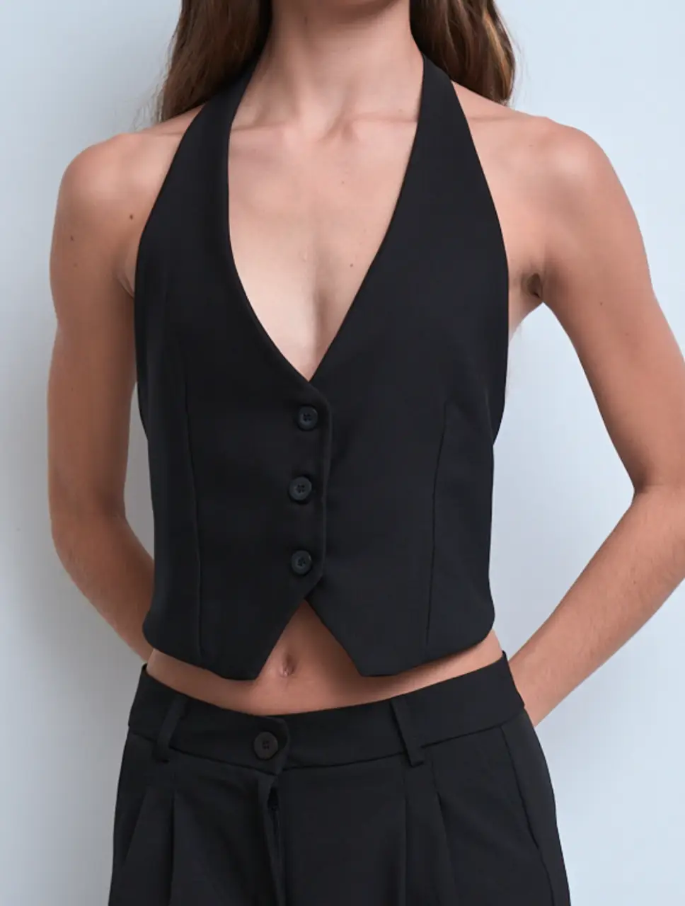Chaleco sastrero negro con diseño halter, de escote en pico y manga sisa. Detalle de abertura en la espalda con pasador de medialuna. Cierre frontal con botones. Perfecto para combinar con pantalones de vestir o faldas. Un básico atemporal para tu guardarropa. Talles S M . Colores disponibles