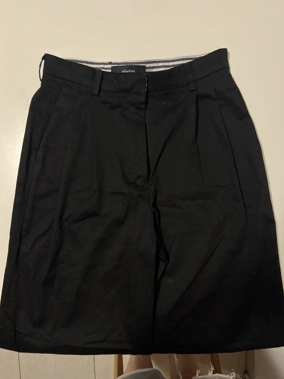Pantalón sastrero negro de la marca Ginebra, con pinzas y bolsillos. Ideal para un look formal o casual elegante.