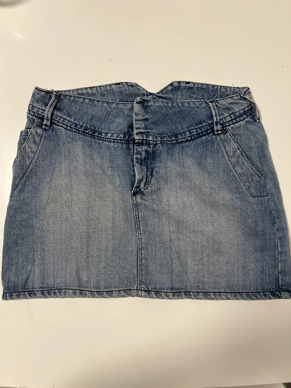 Minifalda de jean azul, tiro medio, con bolsillos delanteros y traseros. Ideal para un look casual y versátil.