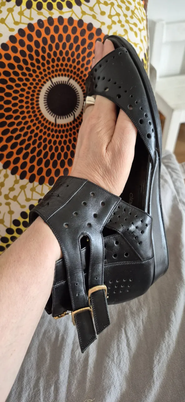 Sandalias negras de cuero con tiras y hebillas doradas. Diseño calado con perforaciones y cierre en el talón para un ajuste cómodo. Ideales para un look canchero y moderno.